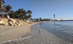 A beach in the foreground with a lighthouse in the background