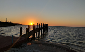 The Sun setting with a wooden dock in the foreground