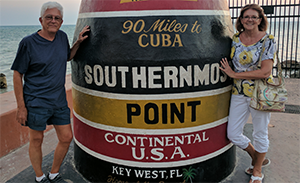 A couple standing next to a landmark showing the most southern place in the US